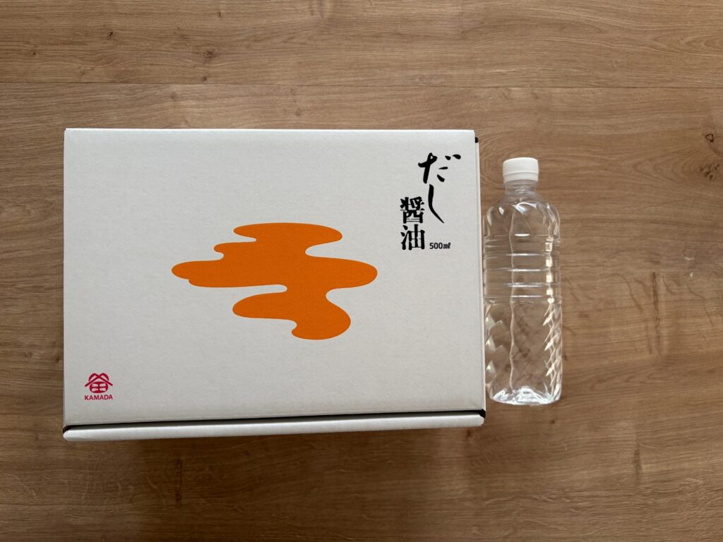 しっかりした白い段ボール箱で届いた鎌田のだし醤油。横に500mlのペットボトルを置いて大きさを比べている