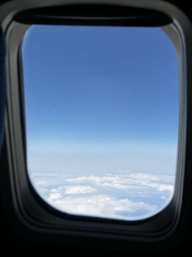 韓国へ向かう飛行機の窓から見た雲の上の青空